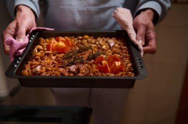 Fırından yeni çıkmış taze biberiye ve fırınlanmış domateslerle süslenmiş ağız sulandırıcı bir fasulye tepsisi. Canlı tonlar yemeğin karşı konulmaz kokusunu vurguluyor..