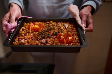 Fırından yeni çıkmış taze biberiye ve fırınlanmış domateslerle süslenmiş ağız sulandırıcı bir fasulye tepsisi. Canlı tonlar yemeğin karşı konulmaz kokusunu vurguluyor..