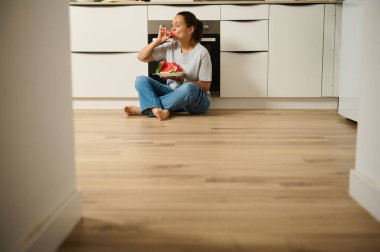 Bir insan mutfak zemininde taze karpuz dilimlerini sever, rahatlama ve basit anları somutlaştırır..