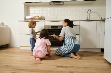 Bir anne ve iki çocuğu modern bir mutfak ortamında neşe içinde birlikte yemek pişiriyorlar. Aile ev yapımı yemekler yapmayı, yaratıcılığı teşvik etmeyi ve sıcak bir iç atmosferde kaynaşmayı seviyor..