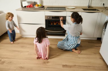 Temiz bir mutfakta, bir annenin taze kruvasan pişirdiği ve çocukların izlediği, sağlıklı bir atmosferin keyfini çıkardığı bir aile anı..