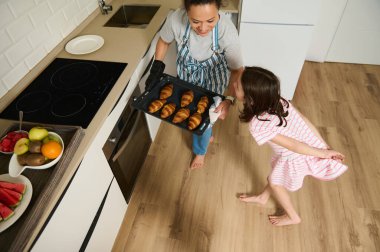 Parlak bir mutfakta bir anne, fırından yeni çıkmış, mutlu çocuklara ev yapımı kruvasan servis eder. Bu neşeli aile anına meyveli sağlıklı bir kahvaltı eşlik ediyor, ev yemeği aşkını gösteriyor..