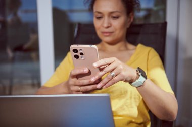 Açık havada rahat bir ortamda akıllı telefon kullanan nişanlı bir kadın. Modern teknoloji cihazları, gelişigüzel titreşim ve bağlantı odaklı ayrıntılı yaşam tarzı tasviri.