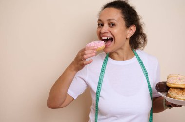 Ulusal Sağlık Ayı ve Krema Dolu Çörek Günü kutlamalarında hoşgörü ve zindelik arasındaki dengeyi sembolize eden, ölçüm bandı takan neşeli bir kadın..