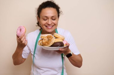 Sevinçle poz verirken çöreğe olan sevgisini kucaklayan neşeli bir kadın hem tatlıya düşkünlüğün özünü yakalıyor hem de mutluluğu koruyor..