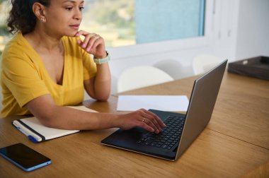 Modern telekomünikasyonu yansıtan dizüstü bilgisayar kullanan bir kadınla rahat bir ofis düzeni. Minimalist çevre, sakin bir ortamda iş ve hayatı dengelerken odaklanmayı artırır..