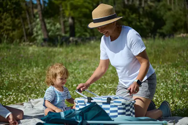 Neşeli bir kadın ve küçük bir çocuk dışarıda kaliteli zaman geçirir. Yeşilliklerle çevrili bir pikniğin tadını çıkarırlar. Aile bağını ve doğayla bağlantıyı sembolize ederler..