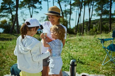 Bir anne güneşli bir yaz günü sakin dağlarda piknik yaparken çocuklarıyla neşeli anlar paylaşır. Beraberlikten, doğadan ve açık hava aktivitelerinden gülümseyerek ve özenle hoşlanırlar..