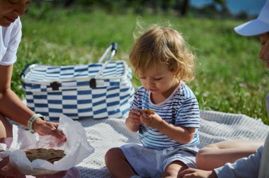 Anne ve çocuklar dağlarda pikniğin tadını çıkarıyorlar. Güneşli bir gün, harika yemekler ve kaliteli aile bağları..