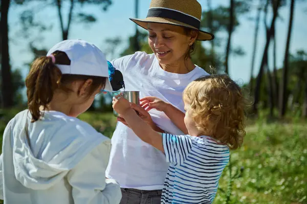 Bir anne, doğa pikniği sırasında çocuklarıyla dışarıda kaliteli zaman geçirir. Güneşin tadını çıkarır ve manzaralı dağ manzarası arasında bağ kurar..