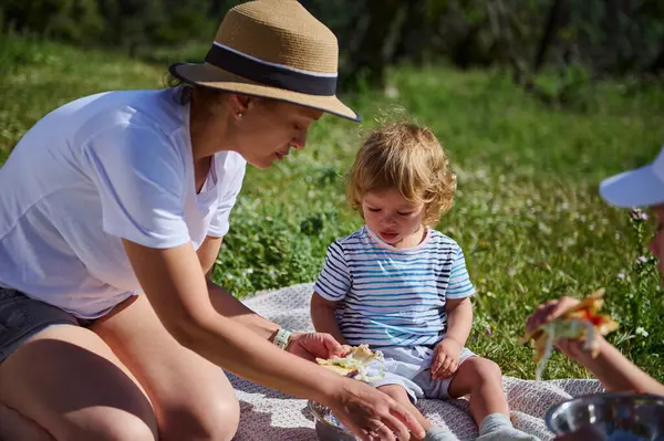 Bir annenin, yaz güneşinin altında doğal güzelliklerle çevrili bir piknik sırasında çocuğuyla neşeli bir zaman geçirmesi gibi büyüleyici bir aile anı..