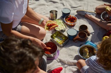 Ebeveynler ve çocuklar sakin bir açık hava pikniğinin tadını çıkarıyorlar, tacoları paylaşıyorlar ve doğayla iç içe geçiyorlar. Atmosfer aile bağlarını, sağlıklı beslenmeyi ve aktif bir yaşam tarzını yansıtıyor..
