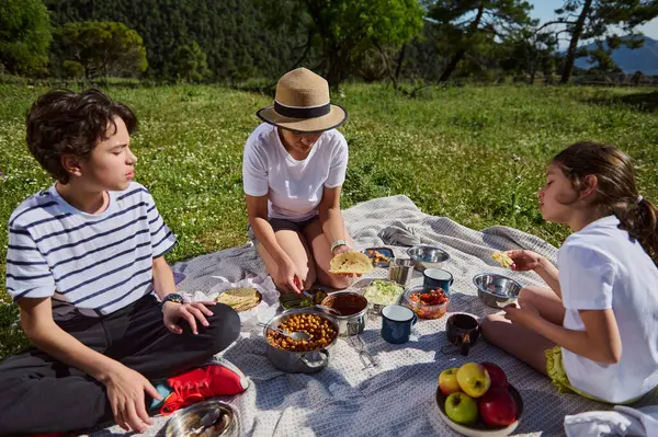 Manzaralı bir dağ manzarasında piknik yaparken aile bağı. Yemek takoları içerir, ve hava neşe, birlik ve rahatlama ile doludur, dışarıda sağlıklı aile zamanlarını somutlaştırır..