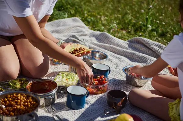 Açık havada pikniğin tadını çıkaran bir aile. Ev yapımı takoları taze malzemelerle paylaşıyorlar. Beraberliği, mutluluğu ve huzurlu doğal ortamda aktif ve sağlıklı bir yaşam tarzını yakalar..