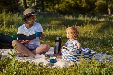 Neşeli bir anne ve çocuğu canlı doğayla çevrili barışçıl bir pikniği, bağları ve boş zamanların güzelliğini paylaşırlar. Huzurlu bir an. Aile birlikteliğini teşvik eden..