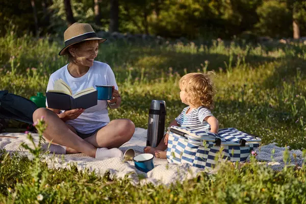 Neşeli bir anne ve çocuğu canlı doğayla çevrili barışçıl bir pikniği, bağları ve boş zamanların güzelliğini paylaşırlar. Huzurlu bir an. Aile birlikteliğini teşvik eden..