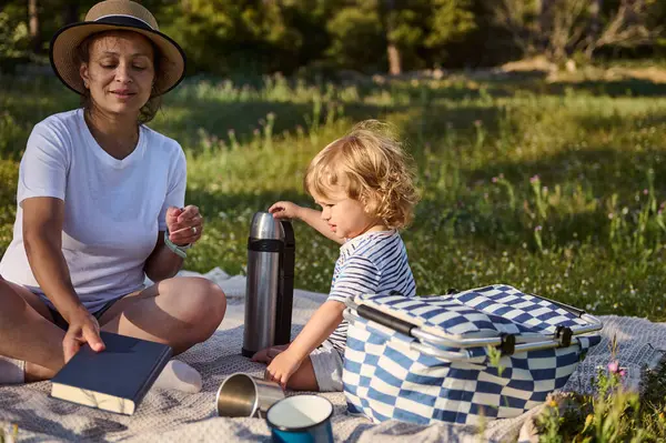 Bir anne ve çocuğun açık havada birbirine bağlandığı hoş bir piknik sahnesi. Arkaplan gibi pürüzsüz, doğal bir ortam. Aile aktivitelerini göstermek için biçilmiş kaftan..