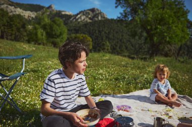 Neşeli bir açık hava pikniği dağlarda kaliteli aile zamanlarını yakalar. Beraberliği, mutlu anları ve doğayla bağlantıyı tasvir eder. Aktif ve sağlıklı bir yaşamı teşvik etmek için mükemmeldir..