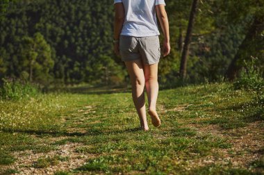 Çıplak ayakla gezen bir kadın yemyeşil kırsallarda dolaşır, sükuneti ve doğayla bağlantıyı vurgular. Dışarıdaki dingin havayı bu güzel ortamda deneyin..