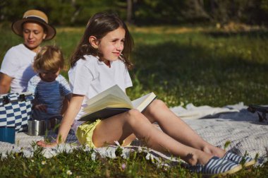 Neşeli bir aile rahatlaması anı, güneşli bir günde pikniğin keyfini çıkaran bir anne ve çocuk, birlikteliği, rahatlığı ve aktif yaşam tarzını sembolize ediyor..