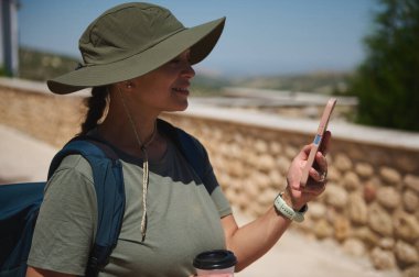 Güneşli bir günde, tarihi mimari ve manzaralı manzaralarla çevrili bir gezgin fotoğraf çekmek için durur. Aktif turizmin özünü ve doğayla bağlantısını yakalıyor.