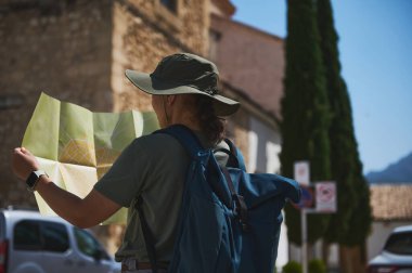 Haritalı bir maceracı çarpıcı dağlarla çevrili pitoresk bir tarihi köyde geziniyor, güneş ışığı altında manzaralı bir Akdeniz manzarasının cazibesini yakalıyor..