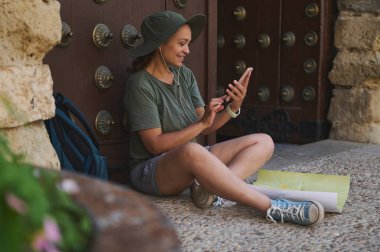 Ortaçağ şehir kapısında telefon ve haritayla meşgul olan yalnız bir gezgin oturuyor. Gezgin şehvet ve açık hava macera temaları için ideal..