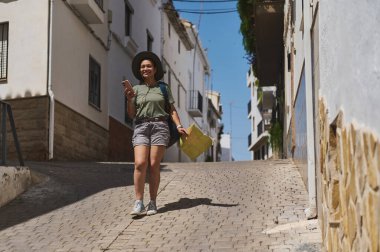 Genç bir kadın ortaçağ köyünde bir keşiften zevk alıyor, bir haritaya danışıyor ve sıcak güneşin altında manzaranın güzelliğini kavrıyor..