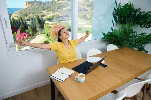 Kendine güvenen bir kadın evinde manzaralı manzaralarla çevrili bir rahatlama anından hoşlanır. Uzaktan çalışma projeleri sırasında işi ve eğlenceyi birleştiriyor. Denge ve üretkenlik kavramı.