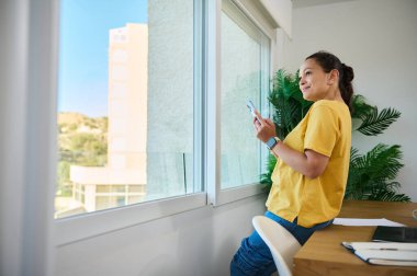 Modern bir çalışma alanında dinlenirken kendine güvenen girişimci planlama projeleri. Şık bir ev ofisinde profesyonel odaklanma ve kişisel rahatlık arasındaki dengeyi gösteren sakin bir sahne..