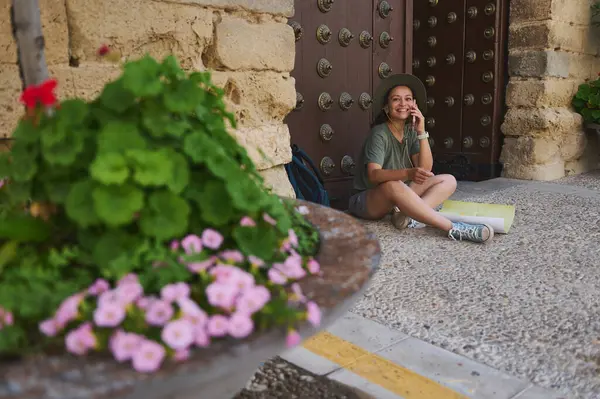 Neşeli kadın dışarıda oturmuş tarihi manzaraları keşfediyor, kültürel seyahatleri ima ediyor. Konforlu giysi ve doğa harmanı zarif tarihsel manzaralar arasında açık hava macerasına ilham verir..