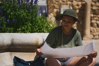 Turist kadın harita incelerken zengin yeşillik ve çarpıcı mimariyle çevrili tarihi bir İspanyol köyünü keşfediyor. Keşif ve kültürel dalgıçlığın bir karışımından keyif alıyor..