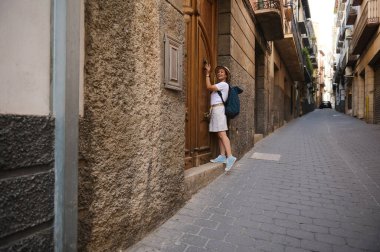 Kentsel keşiflere katılan bir kadın turist, taş cepheleriyle süslenmiş, seyahat ve tarihin özünü yakalayan pitoresk bir caddenin manzarasından zevk alıyor..