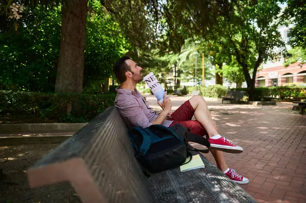 Güneşli bir günde sakin bir parkta gazete okuyan bir adam. Sakinliği, rahatlığı ve boş zamanı doğa ve yeşilliğin ortasında geçirmenin zevkini yakalar..