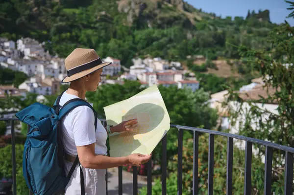 Bir turist bir harita kullanarak tarihi bir şehrin büyüleyici sokaklarında geziniyor, güneşli bir günde manzaranın ve huzurlu atmosferin tadını çıkarıyor..