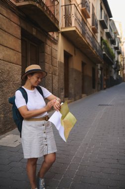 Elinde harita tutan düşünceli bir kadın güneşli bir günde tarihi şehir sokaklarını keşfediyor. Yaz kıyafetleri giyer ve seyahatine çıkar..