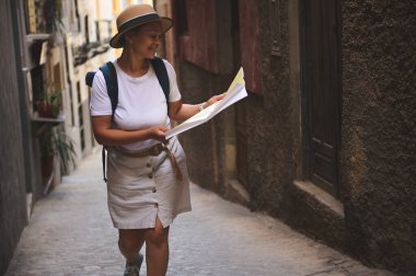 Bir gezgin, bir rehber haritayı incelemek için ortaçağ sokaklarında yürür. Bu keyifli atmosfer, tarihi çevreye bir macera, keşif ve hayranlık hissi veriyor..