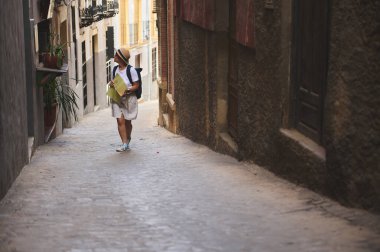 Elinde haritayla dar kaldırım taşlarından geçen bir turist. Sahne, tarihi bir kasabanın cazibesini yakalıyor. Keşif, keşif ve kültürel macera çağrıları yapıyor..