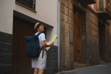 Sırt çantası ve haritası olan kadın bir gezgin, yeni maceralar arayarak ve Avrupa kentsel ortamında tarihi mimariyi takdir ederek, resimli caddeleri keşfediyor..