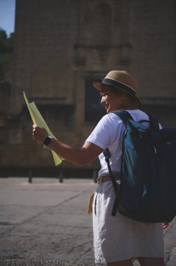 Sırt çantası ve haritası olan bir kadın turist tarihi bir şehir keşfediyor. Gölge niyetine şapka takarak kaldırım taşlı caddelerde geziniyor. Güneşli bir gün büyüleyici şehir atmosferini güçlendirir..