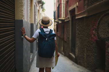 Eski bir şehrin tarihi sokaklarını keşfeden, elinde harita tutan ve şehir keşfi atmosferinin tadını çıkaran sıradan giyinmiş bir kadın..