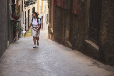 Bir turist, elinde haritayla ortaçağ şehrinin kaldırımlı caddelerini geziyor. Yolculuğu ve otantik miras keşiflerinin atmosferini kucaklıyor..