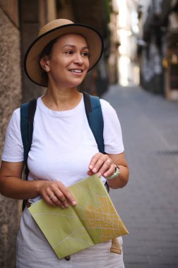 Tarihi şehir sokaklarında elinde haritayla gezen, keşifleri canlı kültürel ortamlarla harmanlayan bir kadının büyüleyici görüntüsü. Seyahat, turizm ve yaşam tarzı temaları için ideal.