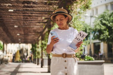 Bir kadın güzel bir şehir caddesini keşfederek rahatlatıcı bir gün geçirmekten zevk alır, bir seyahat rehberi tutar ve akıllı telefonunu navigasyon için kullanır, günlük kıyafetler ve büyüleyici bir şapka giyerek..
