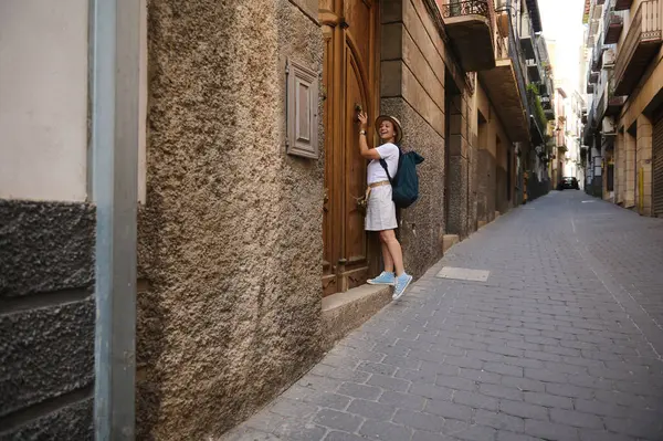 Kentsel keşiflere katılan bir kadın turist, taş cepheleriyle süslenmiş, seyahat ve tarihin özünü yakalayan pitoresk bir caddenin manzarasından zevk alıyor..