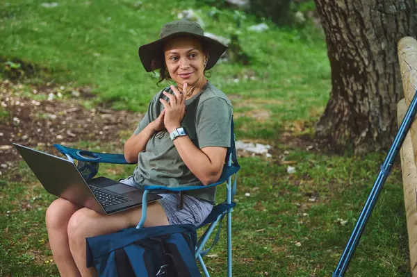 Dıştaki bir hayat sahnesinde bir kadın, dizüstü bilgisayarla sakin bir arka planda birden fazla iş yapıyor. Gelişigüzel bir kamp kurma özelliği, teknolojinin ve doğal çevrenin kaynaşmasını vurguluyor..