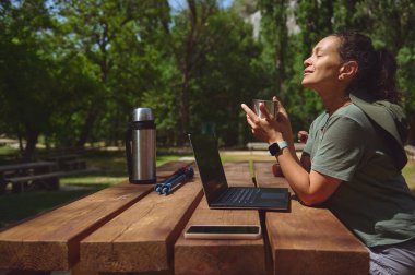 Bir kadın açık havada temiz bir çalışma ortamından hoşlanır. Bir dizüstü bilgisayarla, doğanın güzelliği ve sükunetiyle çevrili dijital göçebe yaşam tarzını kucaklıyor..