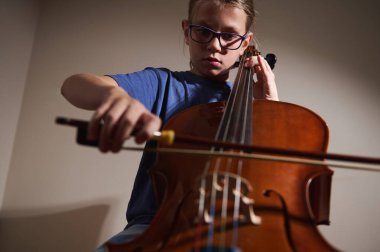 Odaklanmış genç bir çellocu performanslarını yakın ışıklandırma altında çalışır, müziğinde kendini adamışlık ve sanatçılık sergiler..