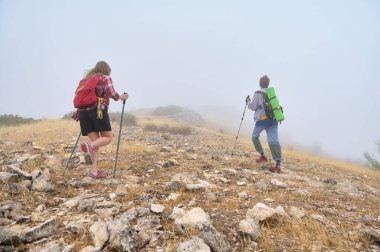 İki yürüyüşçü, sisli kayalık bir dağ yamacından geçer, etkin bir yaşam tarzını ve doğanın tenha güzelliğinin ortasındaki maceralara olan sevgisini somutlaştırır..