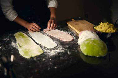 Kadın şef İtalyan bayrağını temsil eden canlı renklerde makarna hamuru hazırlıyor, Ulusal Makarna Günü kutlamaları sırasında İtalyan gastronomi kültürünü ve geleneğini bir zanaatkar mutfak ortamında vurguluyor..